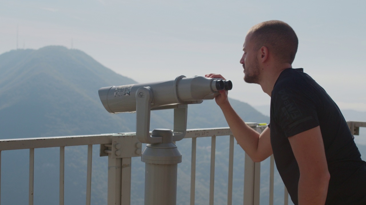 年轻游客用投币双筒望远镜观赏大自然。视频下载