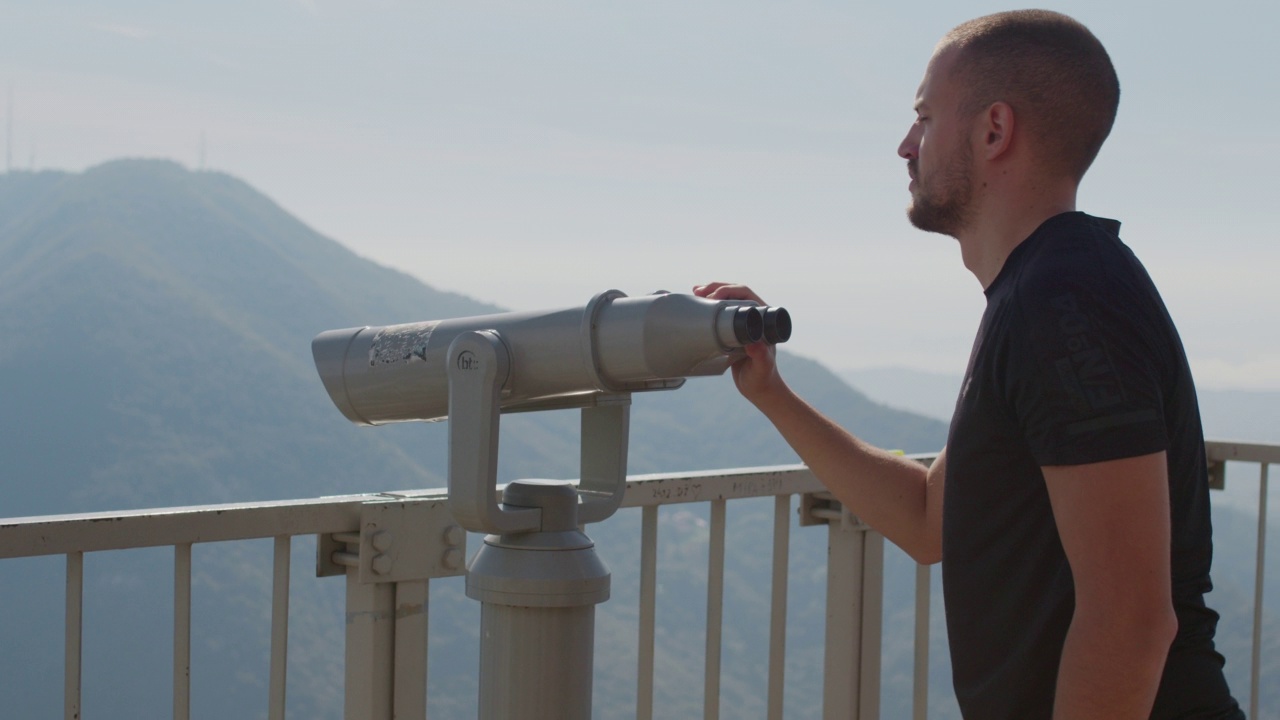 年轻游客用投币双筒望远镜观赏大自然。视频下载