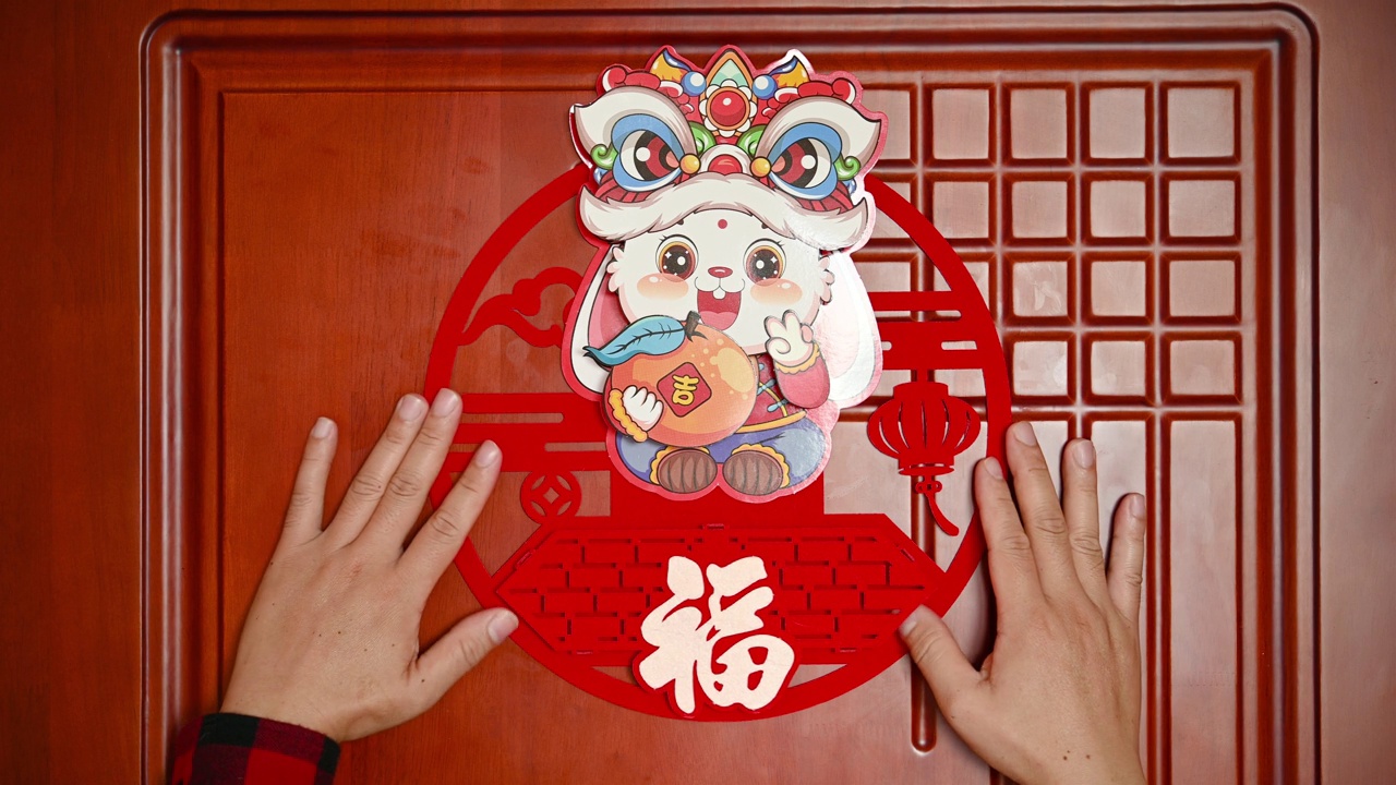 一名男子把中国兔年的装饰贴在一扇门上，在横构图上翻译着汉字，幸运和财富没有标志没有商标视频下载