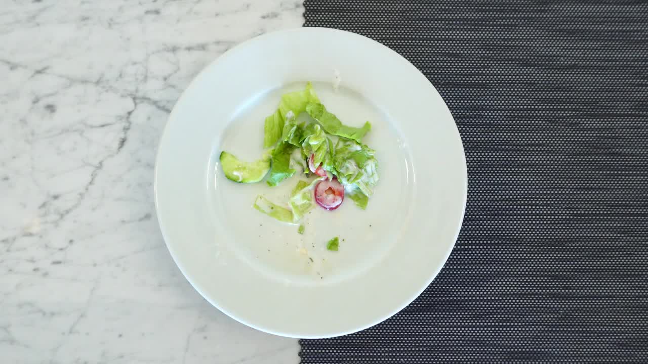 剩下的食物，蔬菜沙拉放在白色的旋转盘子里。从上面看。视频下载