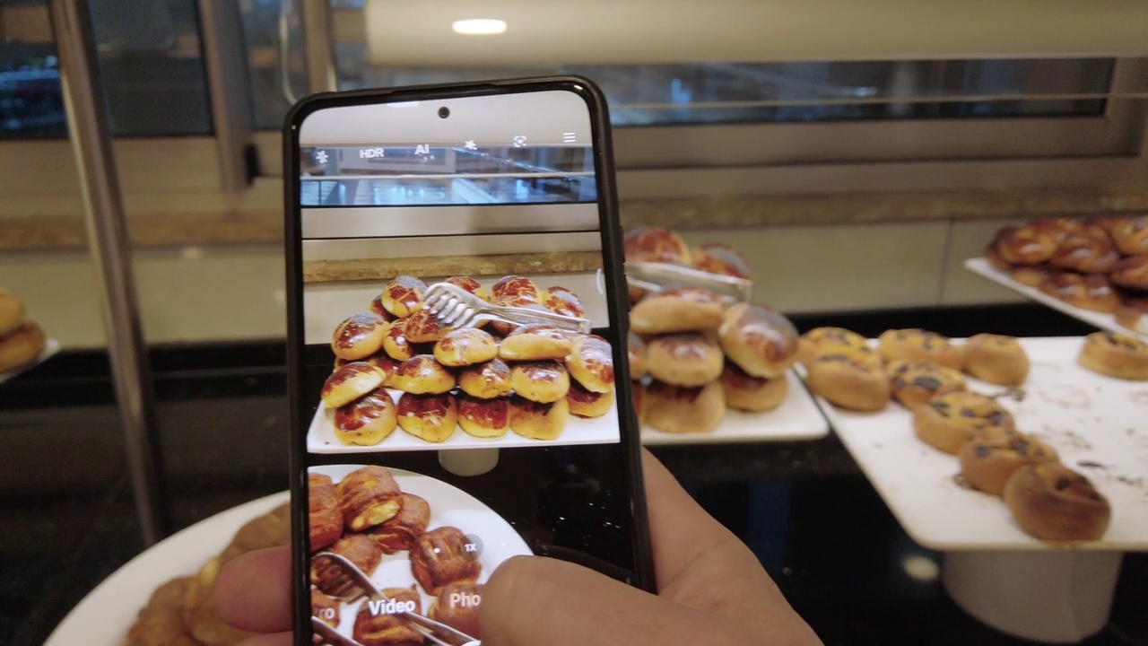 一位年轻的博主正在用智能手机拍摄自助餐厅的食物。社交网络概念。土耳其酒店餐厅。视频下载