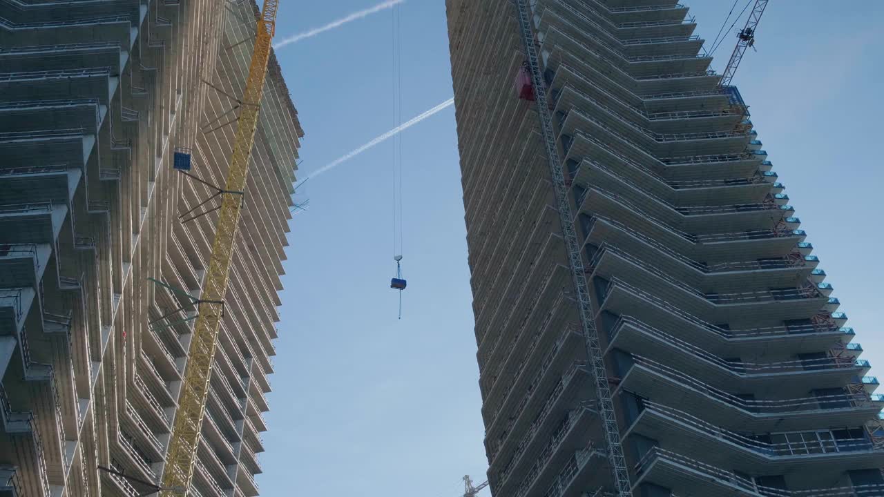 塔式起重机将建筑材料吊到摩天大楼的顶部。新建公寓产业视频素材