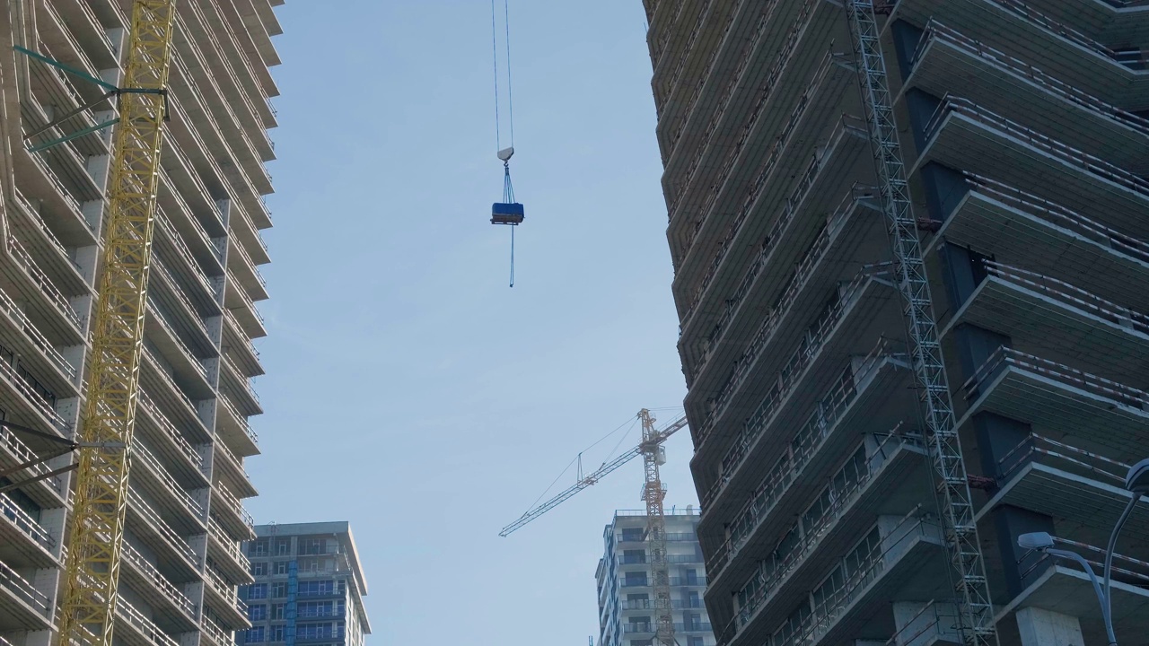 用建筑起重机将建筑材料吊到住宅摩天大楼顶部。房地产开发视频素材