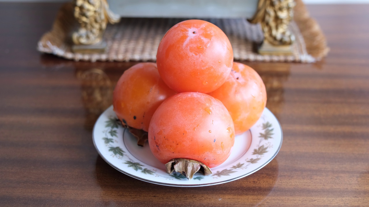 柿果实。新鲜的柿子在复古的背景。卡奇梅子，日本柿子，卡奇柿视频下载