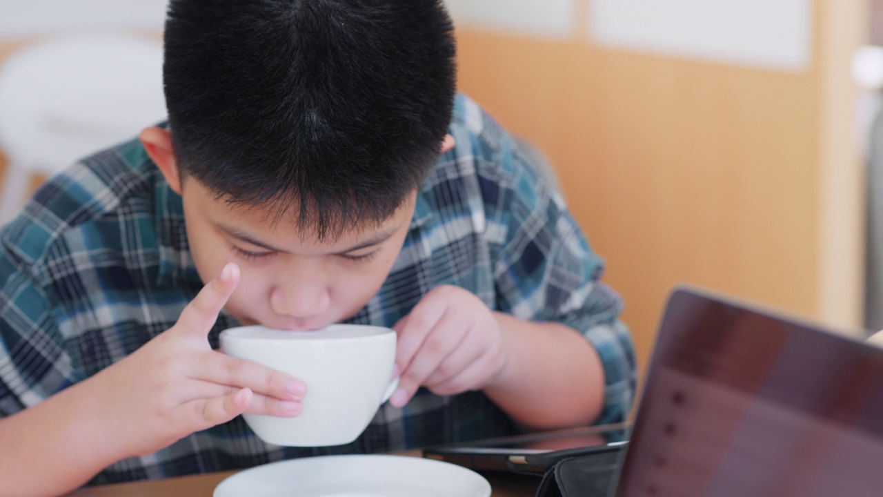 近距离观察亚洲男孩在咖啡馆喝热牛奶视频下载