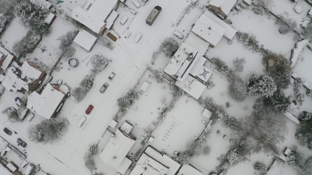 在英国的一个下雪天，无人机在郊区住宅街道上空拍摄视频下载