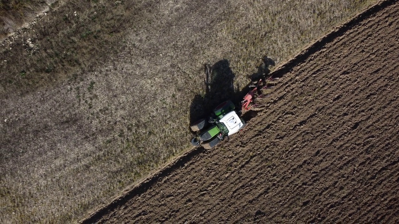 一架农业拖拉机在冬季犁地的鸟瞰图。视频下载