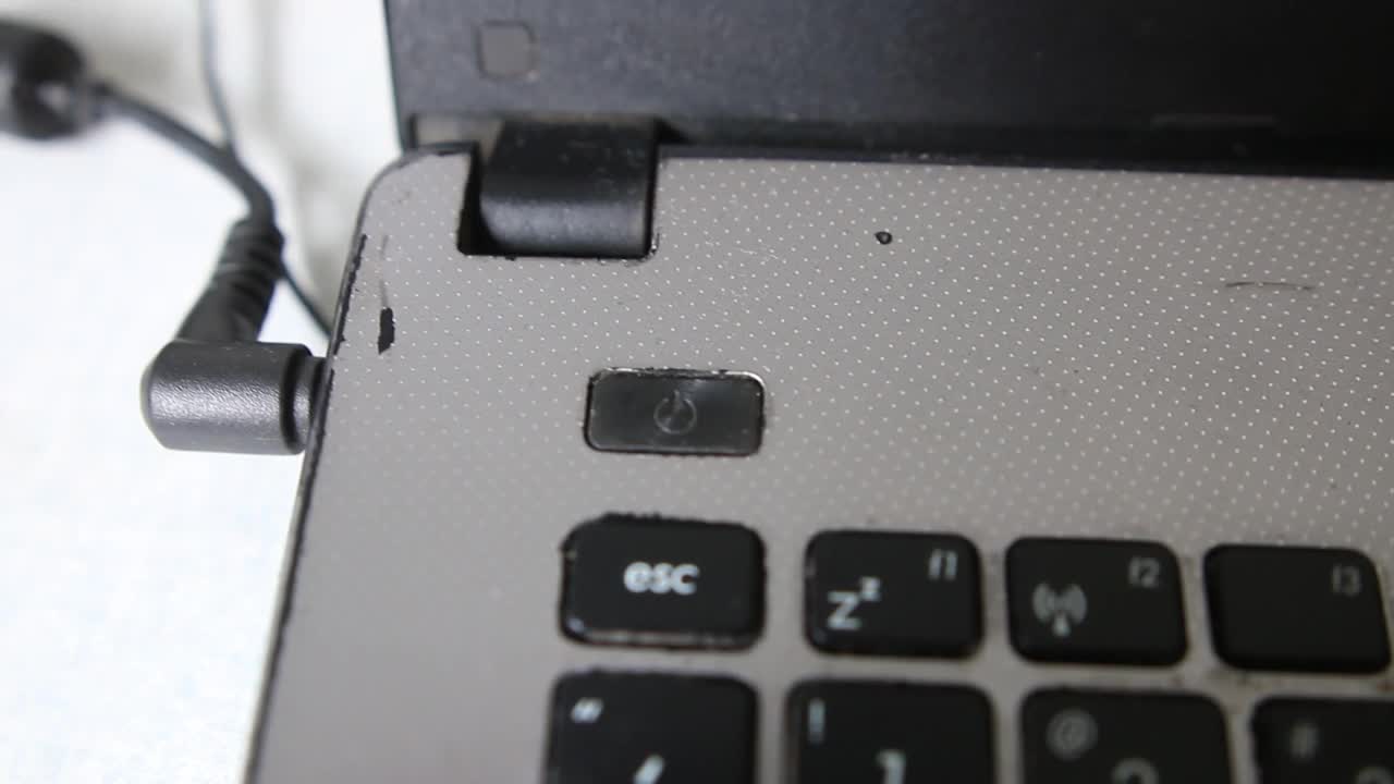 一个男人在一台笨重的笔记本电脑上按下开关键视频素材