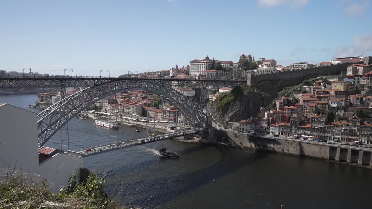 船航行在唐·路易斯一世桥横跨杜罗河和背景里贝拉区，联合国教科文组织世界遗产，波尔图，北，葡萄牙，欧洲视频素材
