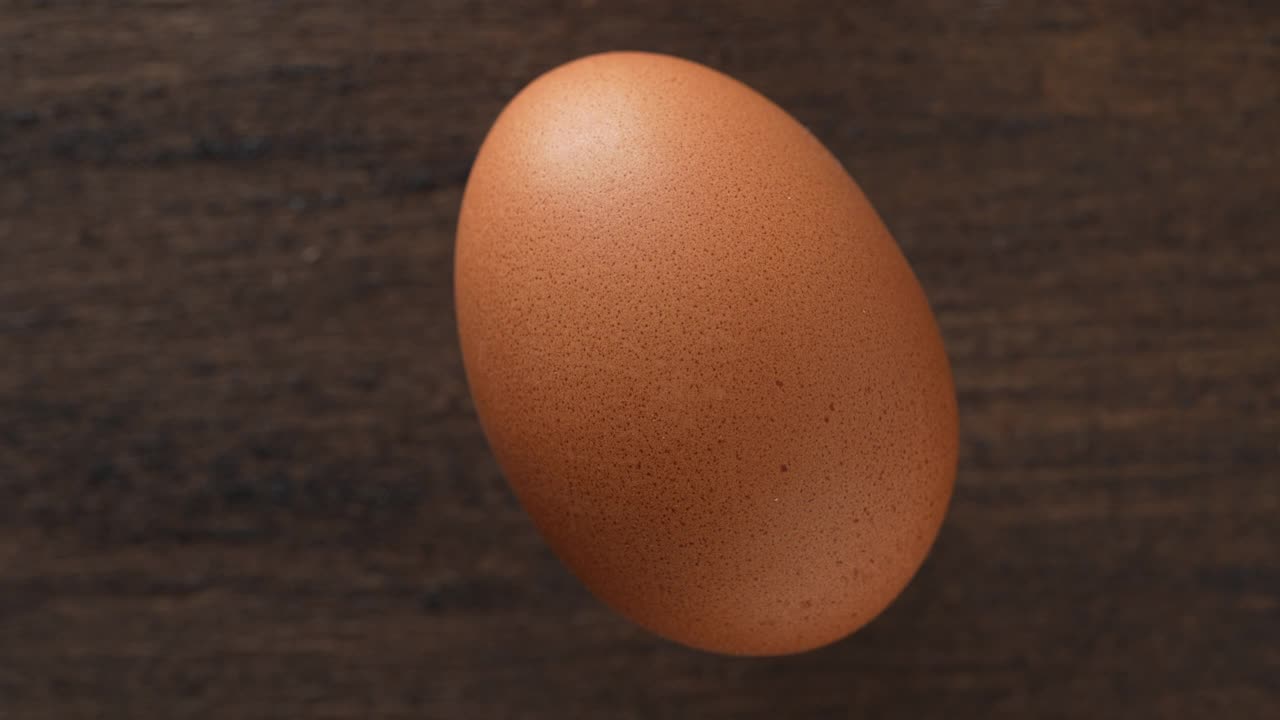 新鲜的一个棕色鸡蛋在木制背景的农业农场，旋转视频下载