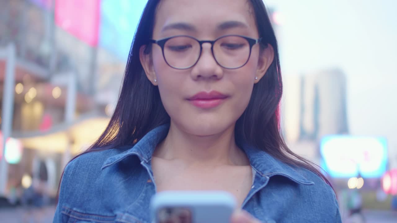 自信美丽的亚洲女人微笑着，拿着手机在网上输入信息进行通信或联系技术。生活方式的人搜索和购物通过应用程序智能视频下载