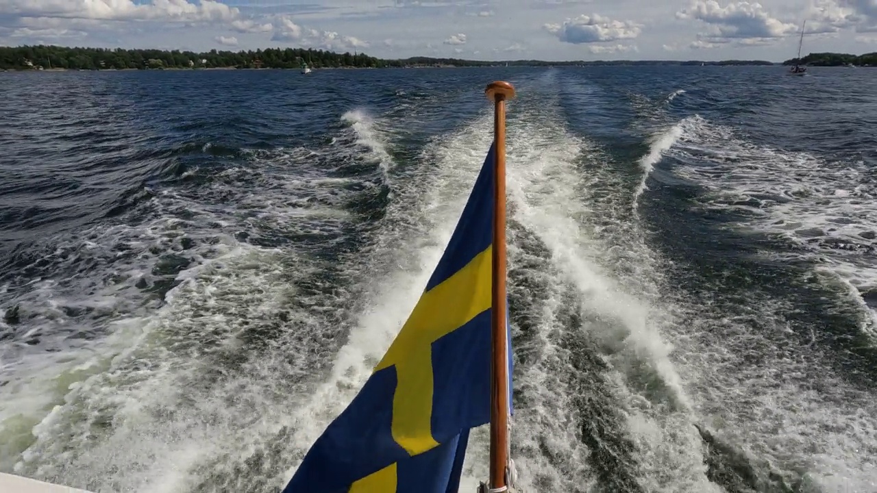 瑞典国旗在斯德哥尔摩群岛航行的船只尾部飘扬。Flag正在录像中视频素材