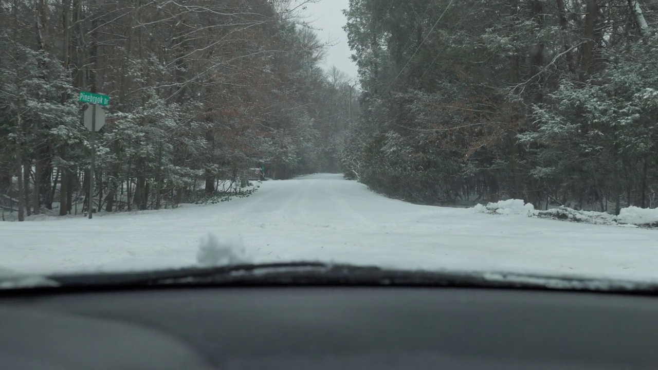 冬天，在宾夕法尼亚州的波科诺，在一场降雪期间，沿着森林开车。视频素材