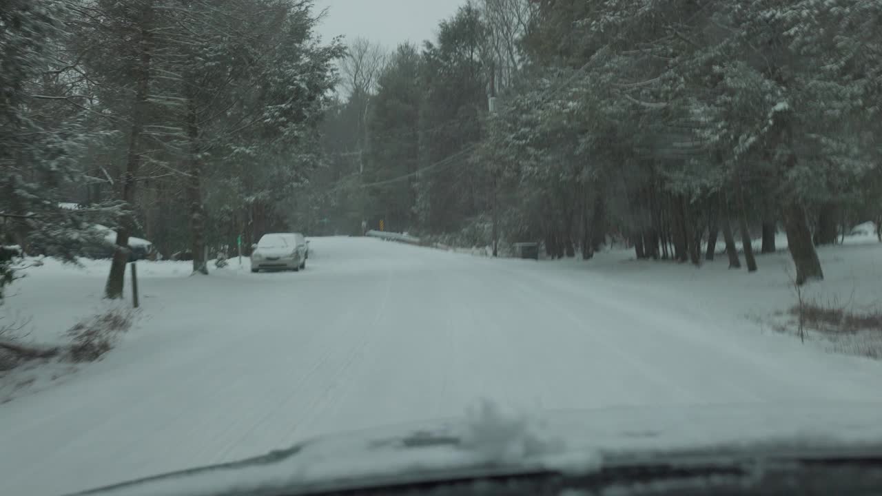 一辆汽车行驶在波科诺森林，宾夕法尼亚州在一个降雪期间。视频素材