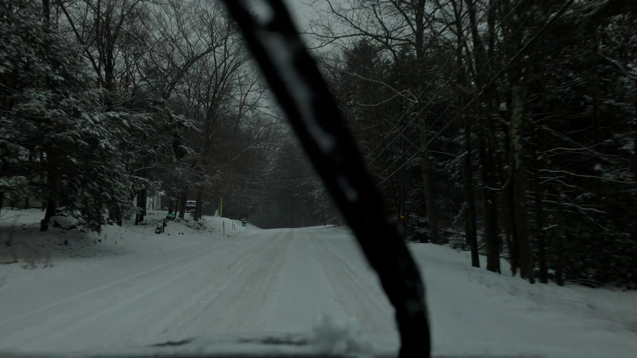一辆汽车行驶在波科诺森林，宾夕法尼亚州在一个降雪期间。视频素材