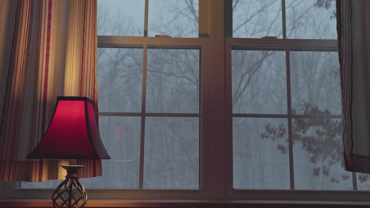 舒适的冬夜在家。透过窗户可以看到白雪覆盖的森林。视频素材