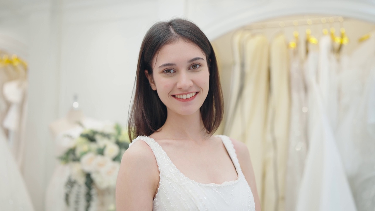在婚礼工作室，穿着白色婚纱的美丽新娘看着相机的微笑视频素材