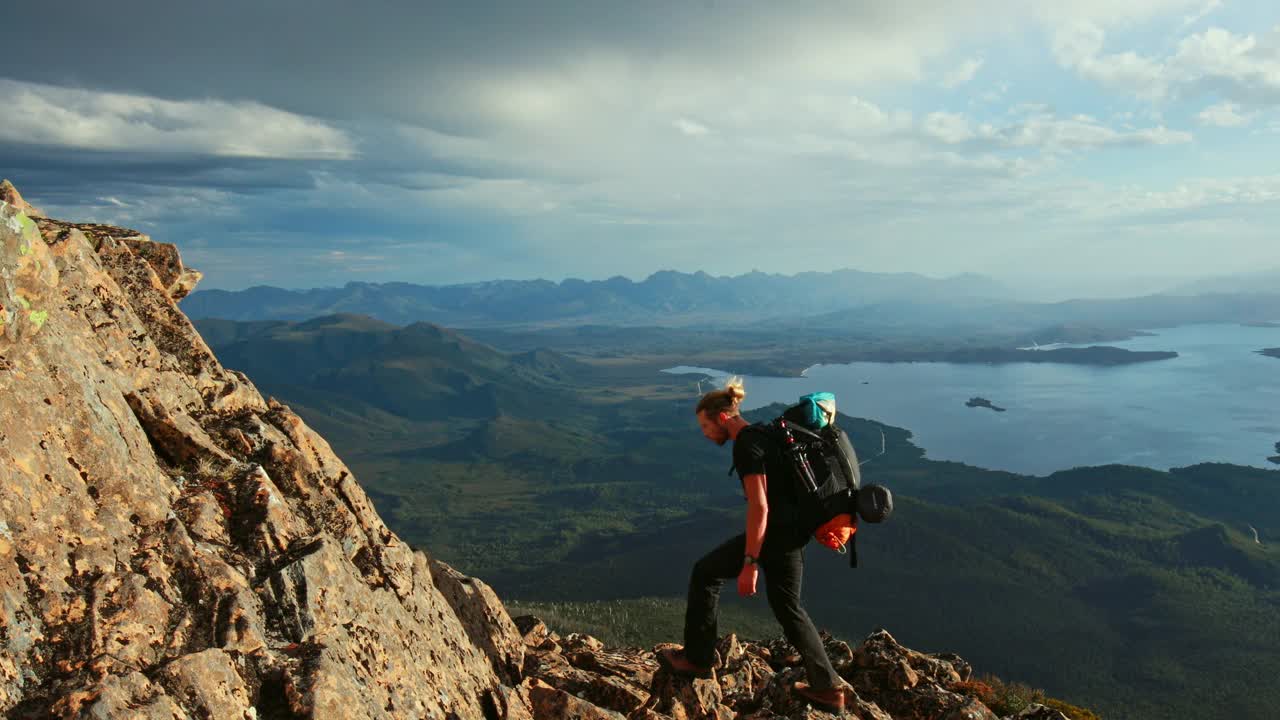 固定镜头的年轻人徒步旅行在一个宏伟的景观场景与山脉和湖泊的背景在塔斯马尼亚州的荒野视频下载