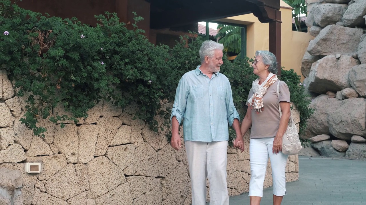 一个快乐和可爱的高级握着退休老人妻子的手的肖像，在日落的背景下一起散步和参观新的地方。一对夫妇在公园里玩得很开心。视频素材