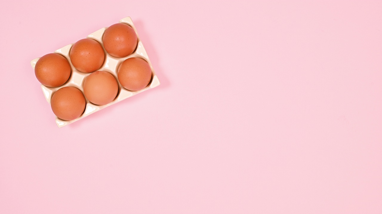 复活节新鲜鸡蛋出现在陶瓷碗鸡蛋在粉彩的粉红色背景。平的。停止运动视频下载