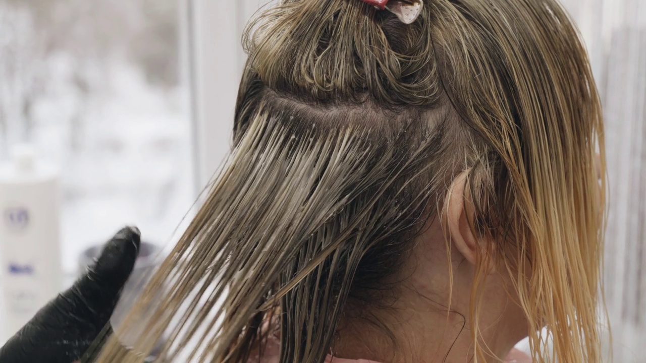 染发师用梳子染发——美容院里的女人用梳子染发。视频素材