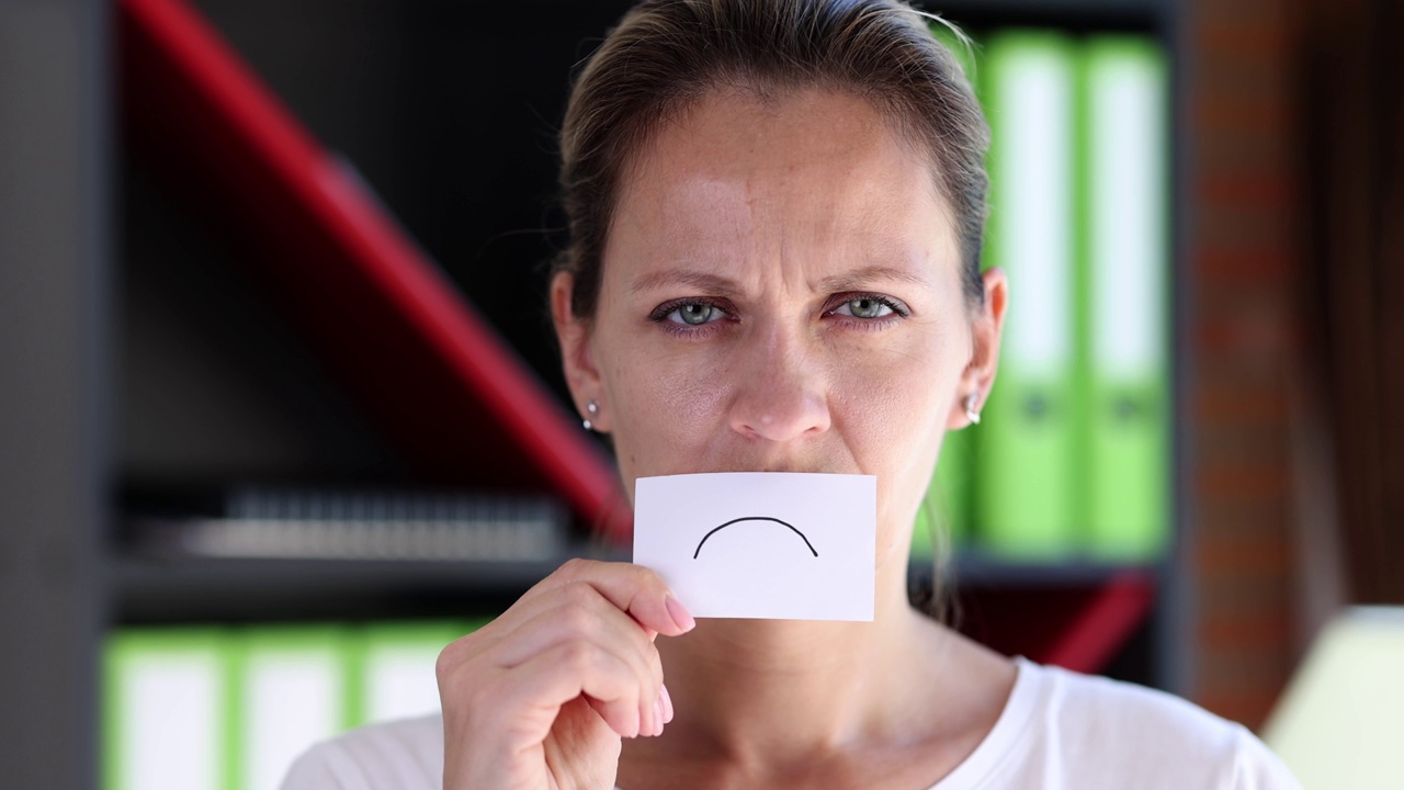 一个悲伤的皱着眉头的女人用纸表情符号覆盖脸的肖像视频下载