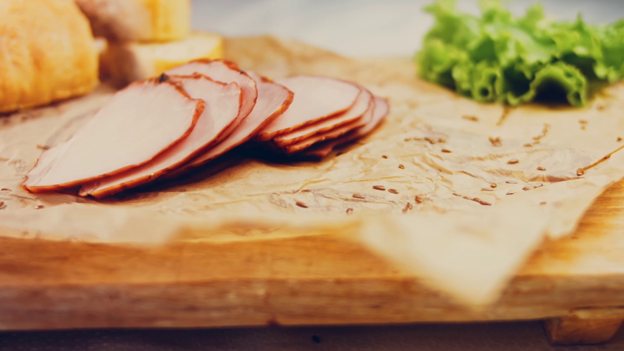 猪肉里脊与法国法棍切片的波浪效果。香肠放在复古风格的烹饪托盘上，放在食物纸上。在滑块上进行慢动作拍摄。我们也用新鲜的生菜叶视频下载