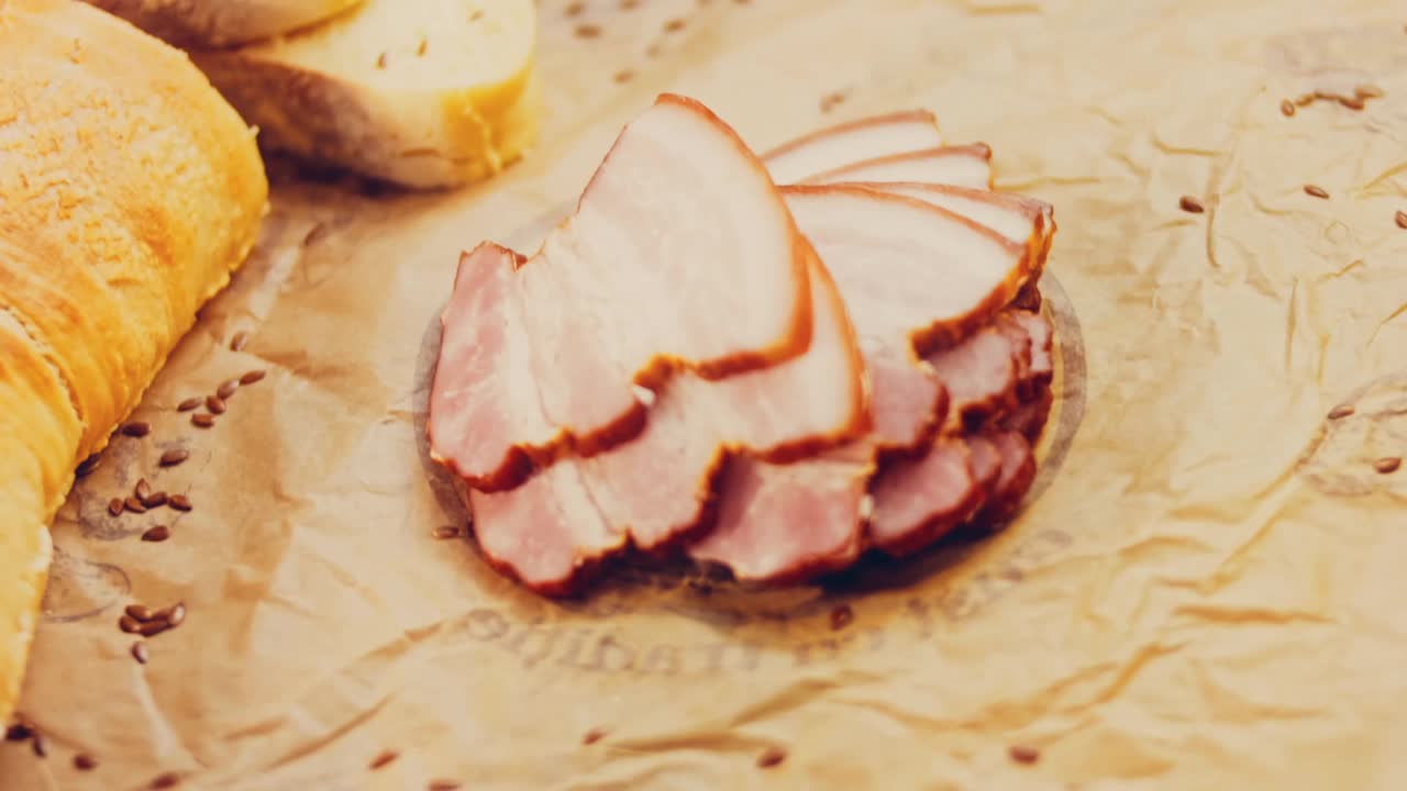 猪肉熏牛肉片与法国法棍的波浪效果。香肠放在复古风格的烹饪托盘上，放在食物纸上。在滑块上进行慢动作拍摄。我们也用新鲜的生菜叶视频下载