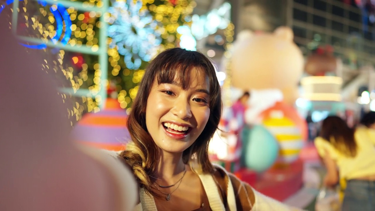年轻的亚洲女子晚上在城市里用手机自拍。视频下载