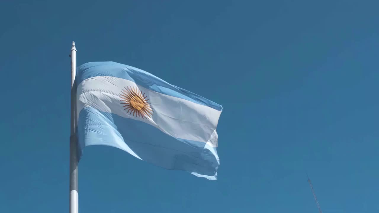 在晴空万里、阳光明媚的日子里，旗杆上飘扬着阿根廷国旗视频素材