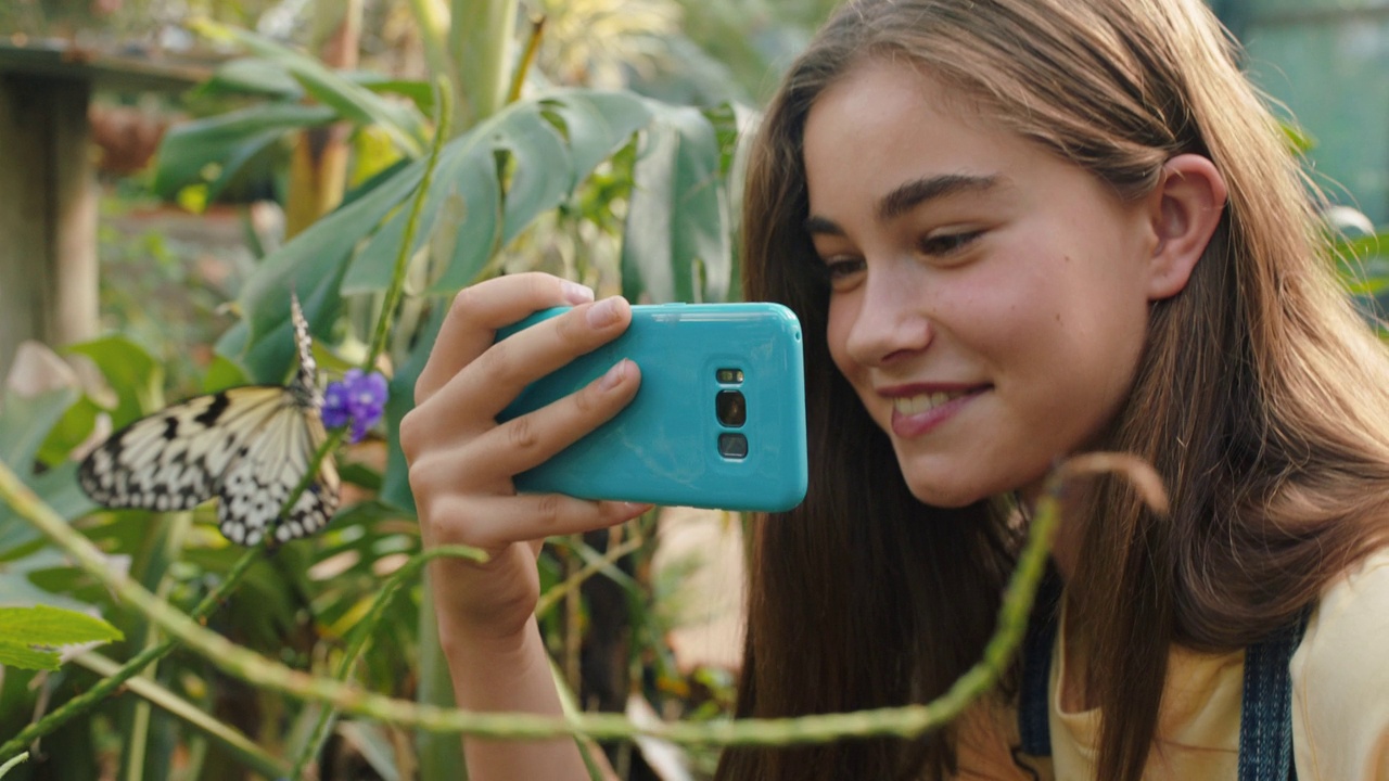 大自然女孩在野生动物保护区用智能手机拍摄蝴蝶的照片，学习自然栖息地，享受动物园远足，在社交媒体上分享环保意识4k视频下载