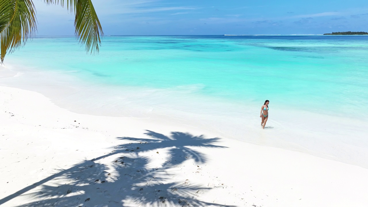 鸟瞰图:一名女子在马尔代夫海滩上散步视频素材