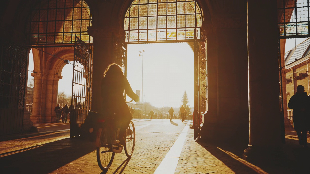 阳光从入口处照在街上骑自行车的人身上视频素材