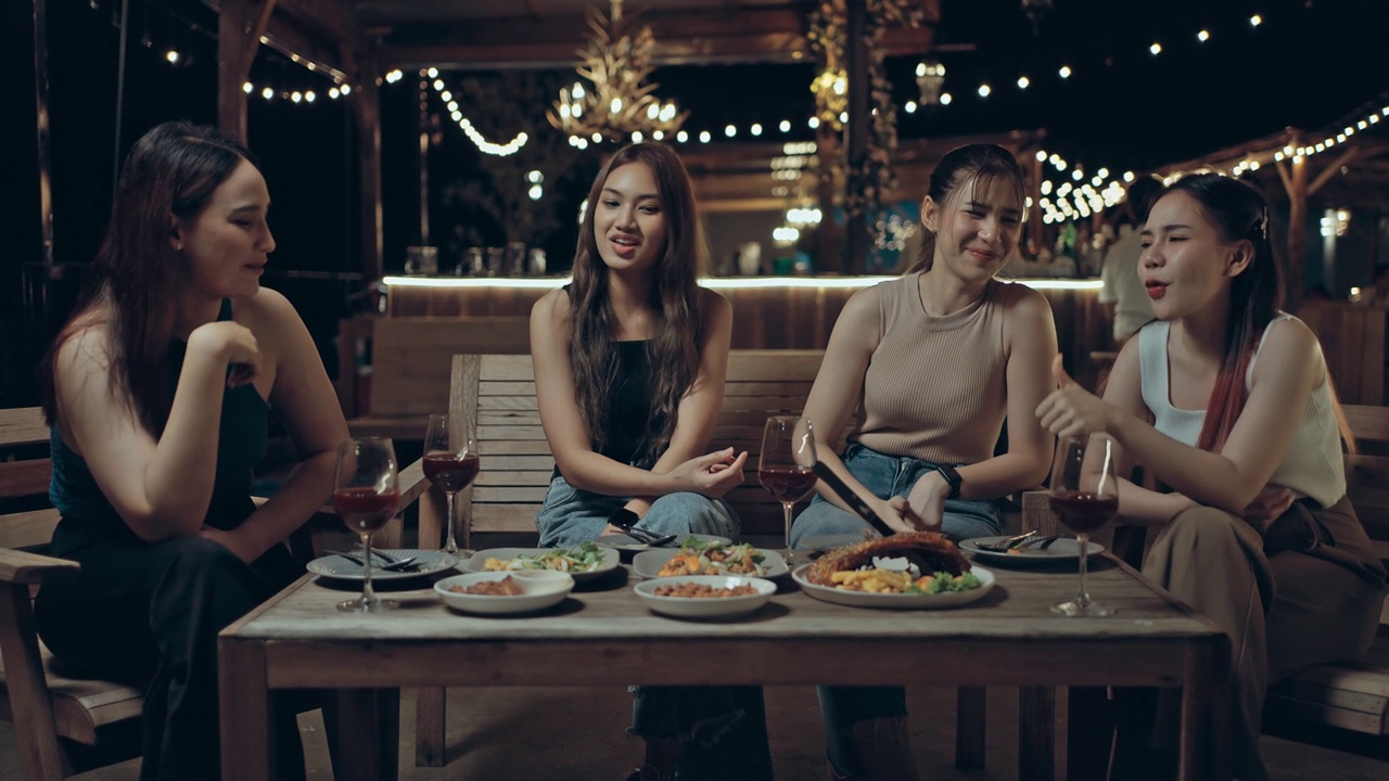 一群亚洲女性朋友在晚上的屋顶派对上一起享受美食。有趣和令人兴奋的休闲活动。视频购买