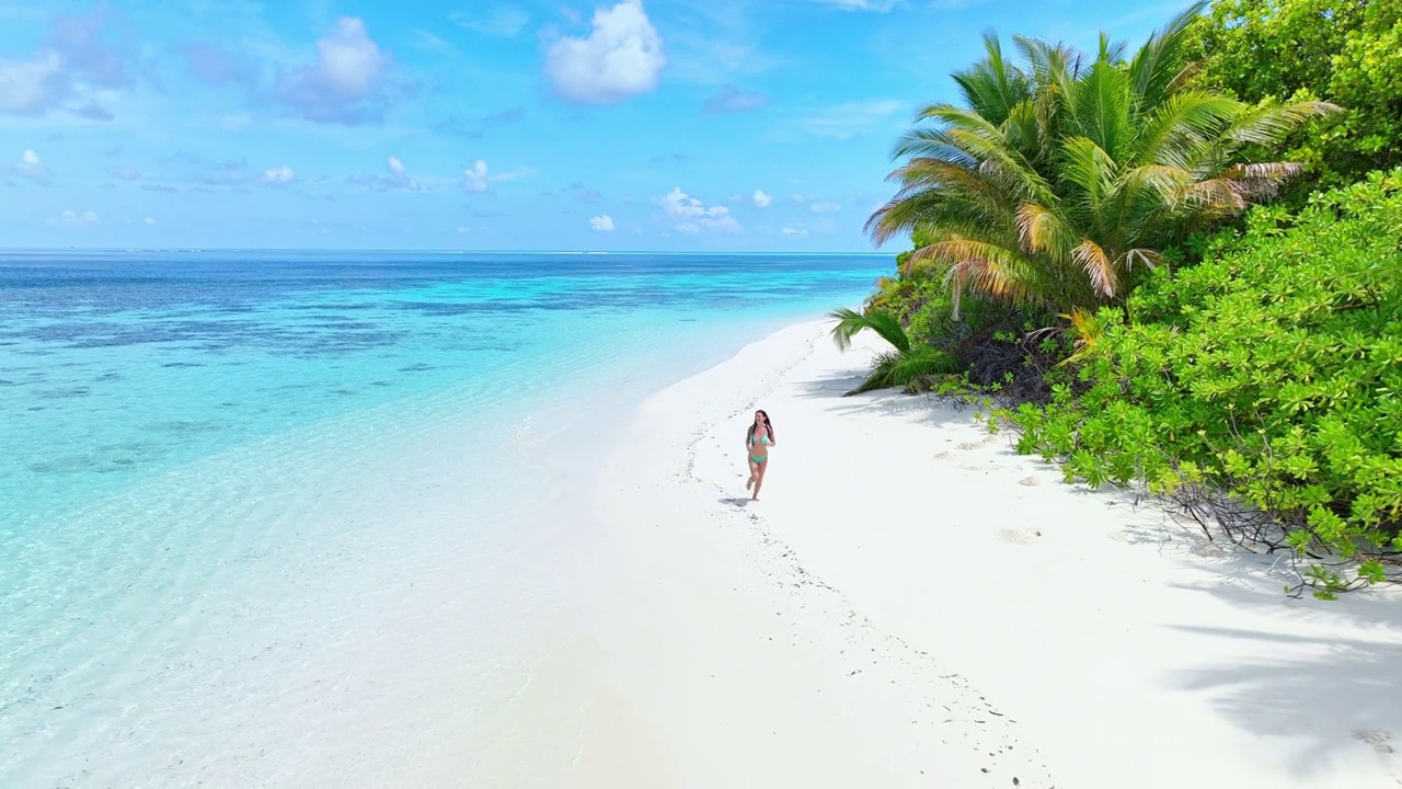 无人机拍摄的年轻女子漫步在热带岛屿的海滩上视频素材