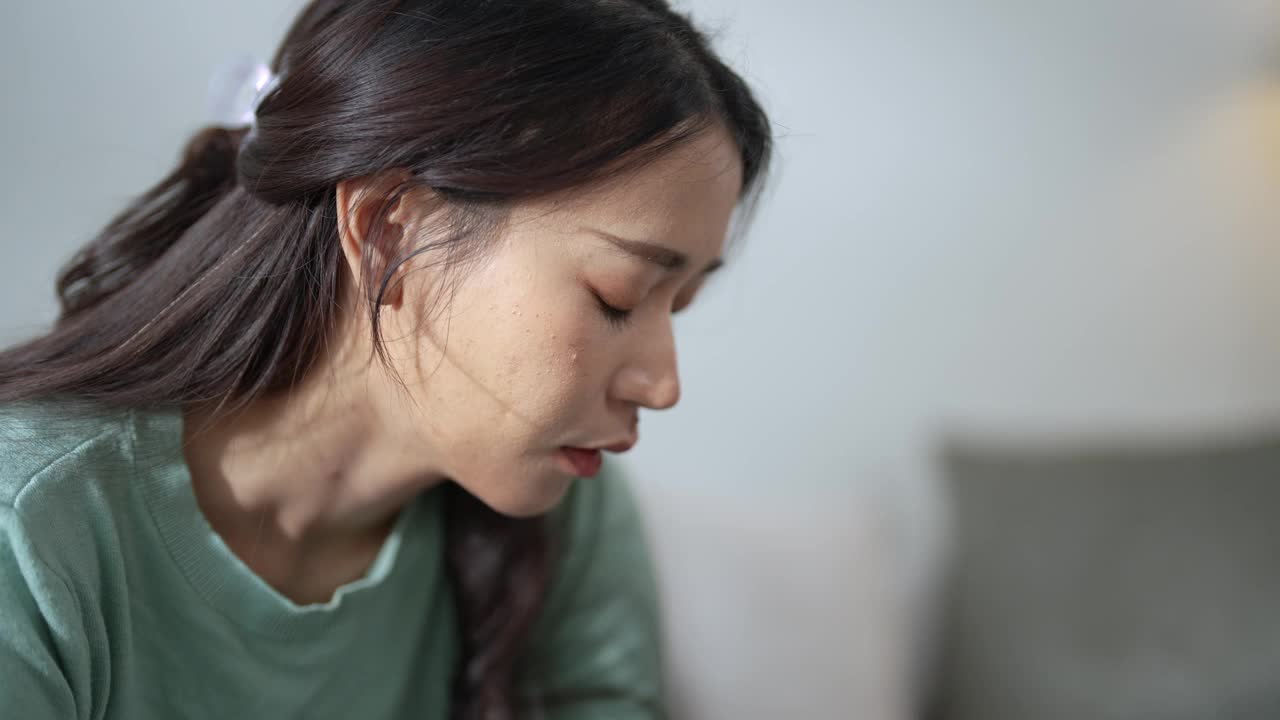 年轻的亚洲女性独自在家时，由于抑郁症状而感到压力和焦虑。视频下载