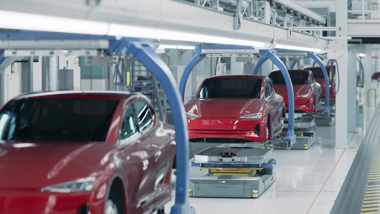 在装配线上，汽车电池被安装在红色电动汽车上。先进自动化明亮工厂的电动汽车生产线。高性能电动汽车制造。视频素材