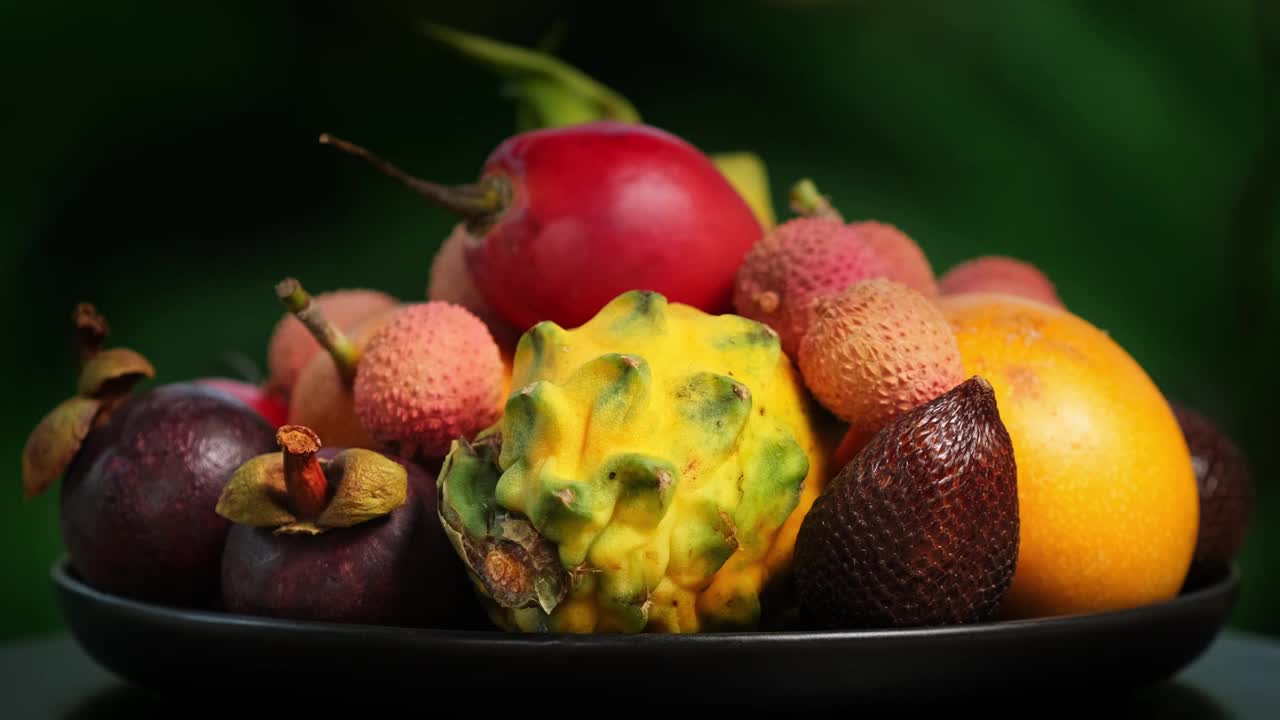 在绿色背景上旋转异国水果(百香果，柽柳，荔枝，Pitahaya, Salak, Granadilla，山竹)视频下载