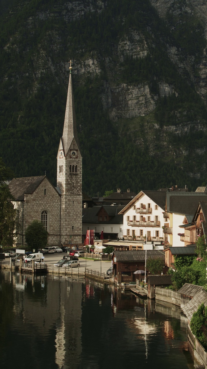 夜间湖滨教堂的宽平移镜头-垂直视频/哈尔施塔特，奥地利视频下载