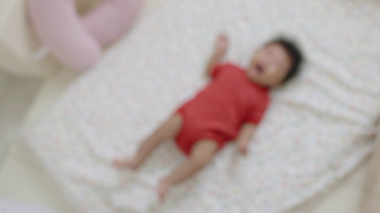 俯视图，一个刚出生的哭闹女婴躺在婴儿床上蠕动时发出很大的声音。视频下载