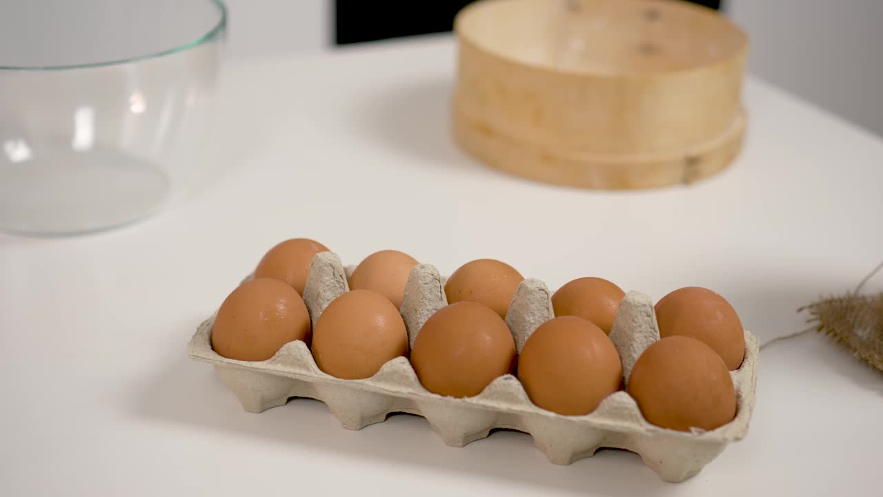 关闭了。全蛋放在容器里。鸡肉棕色新鲜生鸡蛋在纸盒。鸡蛋盒里有十个鸡蛋，旁边是面粉，用来揉面团视频素材