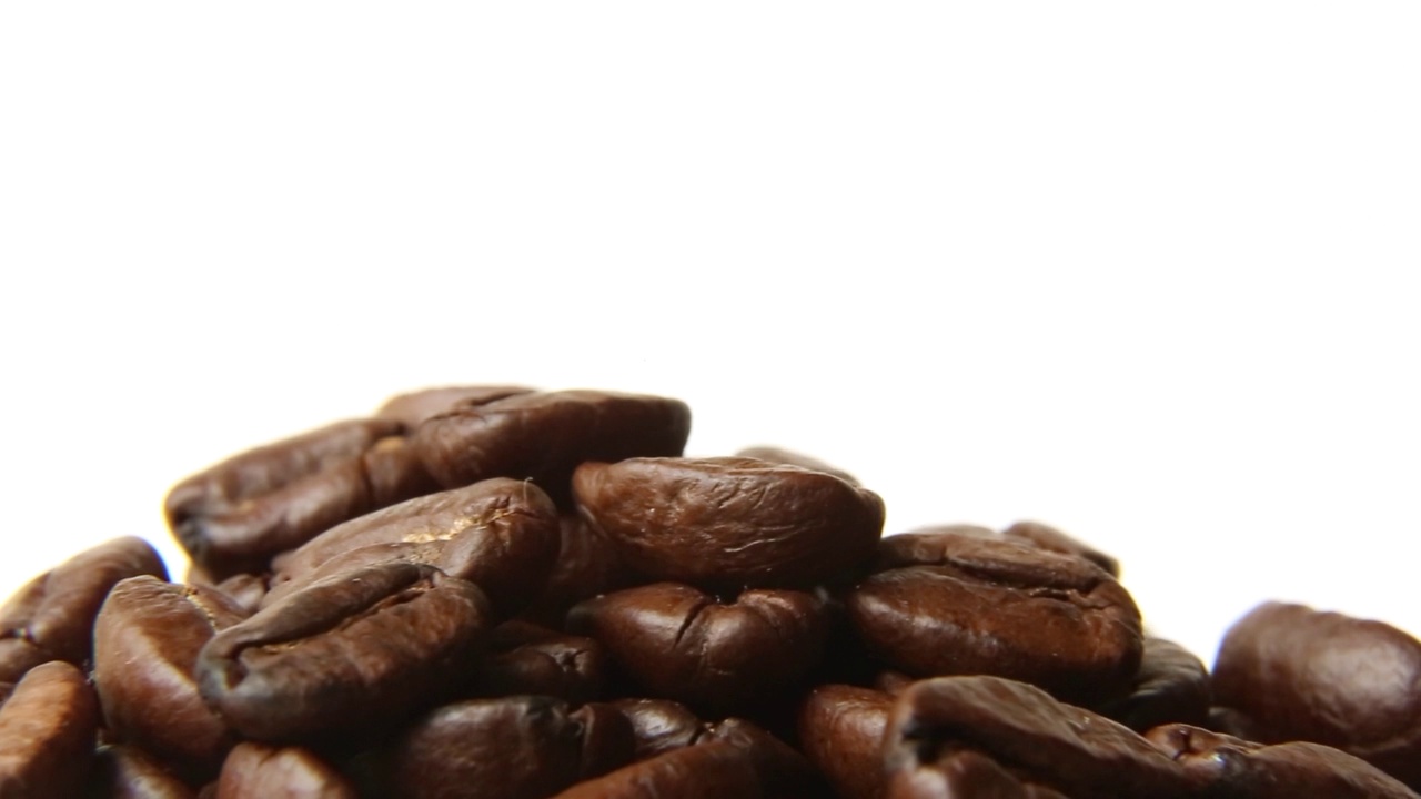 烤好的咖啡豆在白色的背景上旋转。视频下载