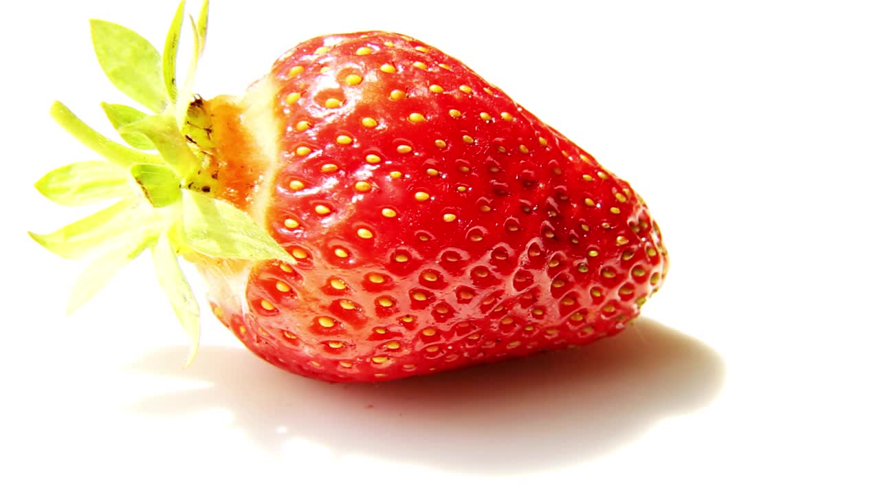 一个新鲜的红草莓在白色的背景上旋转。视频下载
