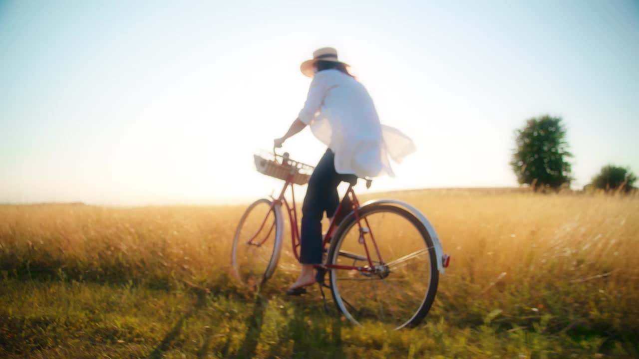 在阳光普照的草地上快乐地骑自行车的女人视频下载