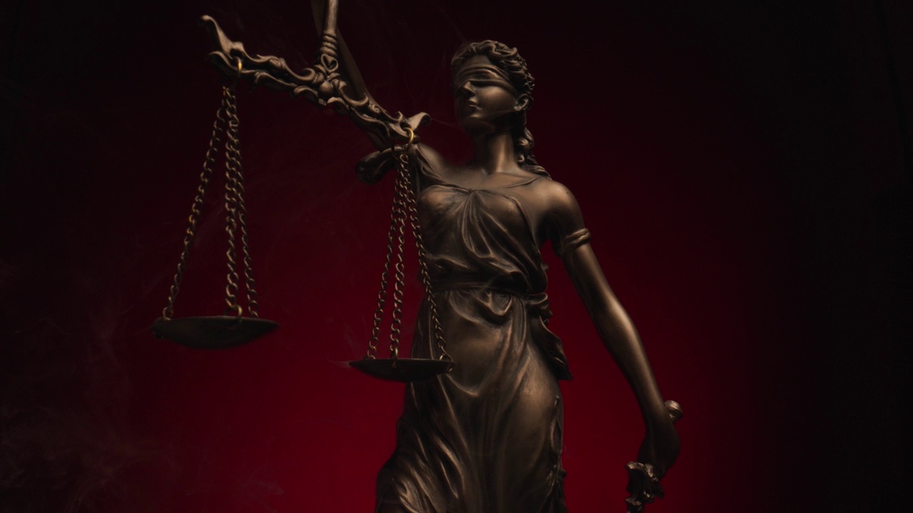 青铜法律雕像的项目视频，象征着平等的概念，她手里拿着比例，在黑色背景与红色背景和烟雾前视频下载