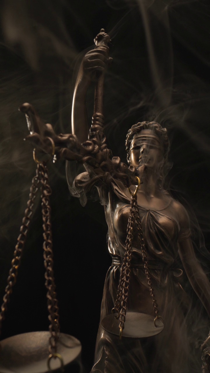 平衡与平等的概念由被蒙住眼睛拿着天平的朱斯蒂亚女神，黑色背景上的烟雾来说明视频下载