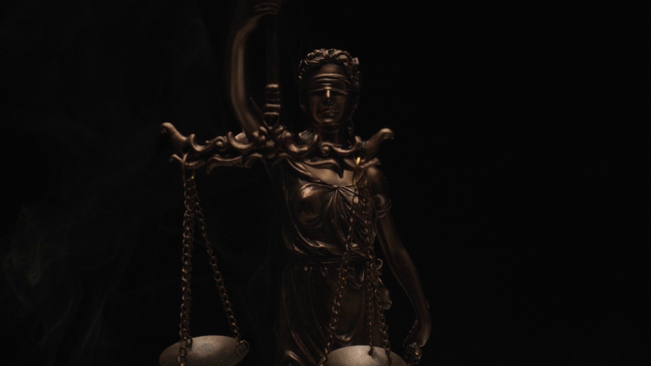 正义的概念由黑色背景上蒙着眼睛的青铜雕像和对与错的比例来说明，带有烟雾的闪光灯视频下载
