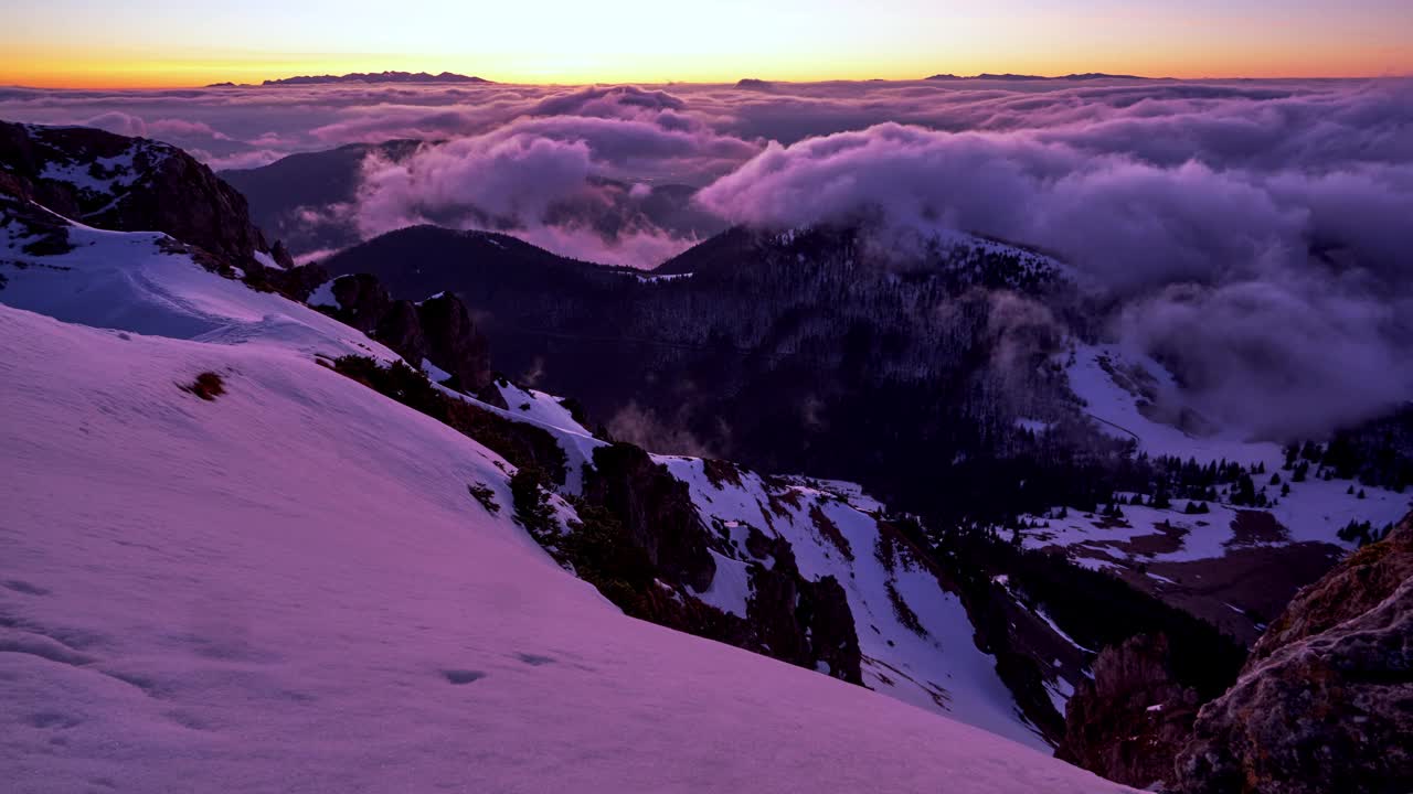华丽的冬季山脉景观，从山顶日出，倒挂的云轻轻地在山区地形上翻滚视频下载