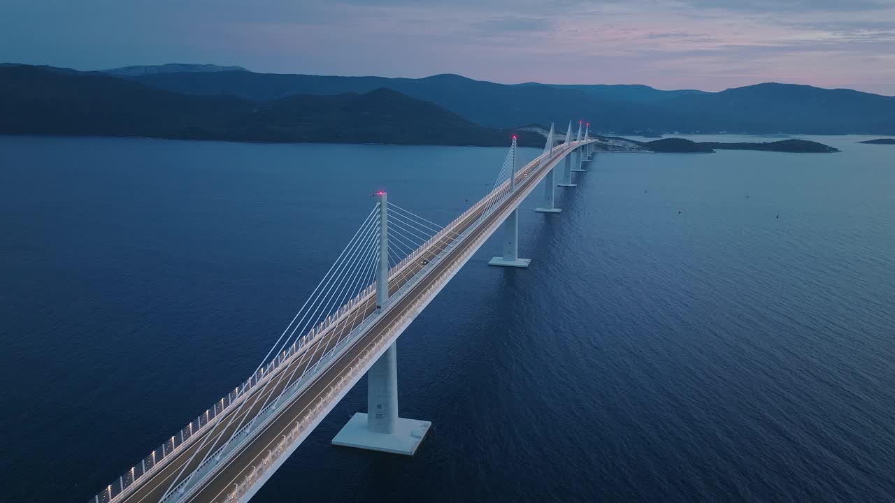 傍晚深蓝色海面上的现代大桥鸟瞰图。汽车驶过地中海上的一座桥。视频素材