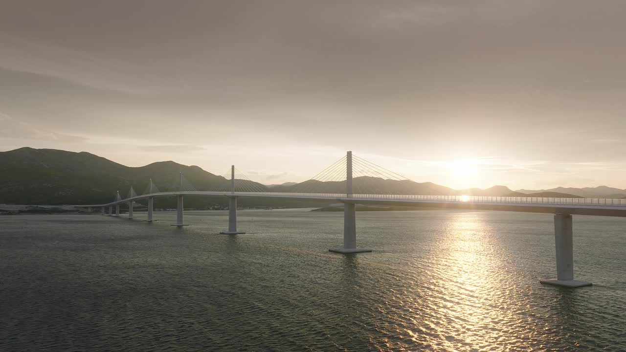 在金色的夕阳下，雄伟的大桥横跨蓝色的地中海。连接岛屿的现代桥梁。鸟瞰图。视频素材